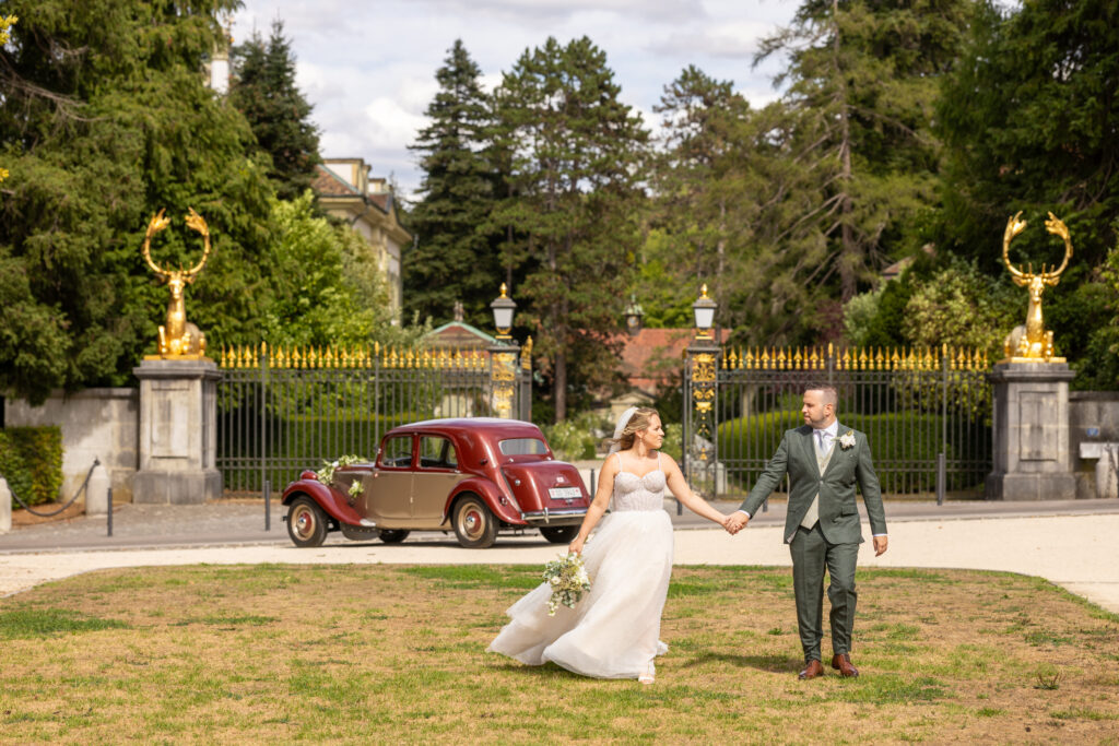 Hochzeit Sand Oase Basel: Pamela und Martin mit rotem Oldtimer vor dem goldenen Tor